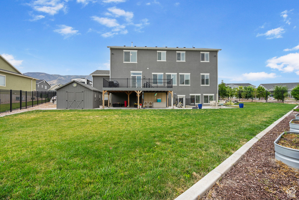 Back of house with a storage shed, a fenced backyard, a deck, a patio, and stucco siding