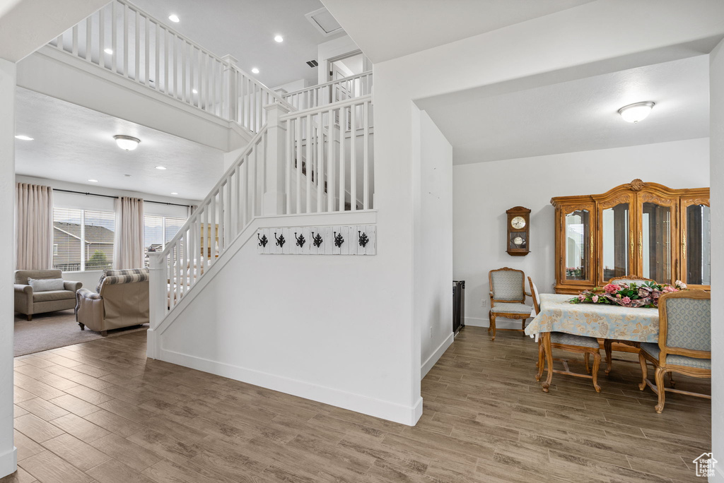 Staircase featuring wood finished floors, a high ceiling, and recessed lighting
