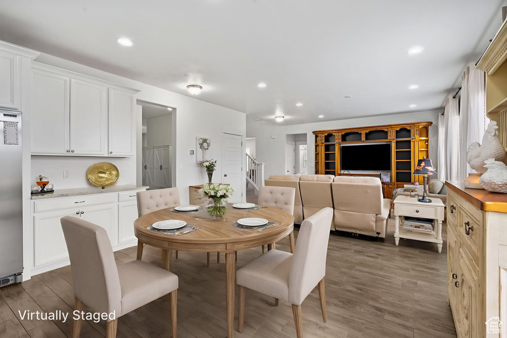 Dining area featuring dark wood-style floors, recessed lighting, and stairs