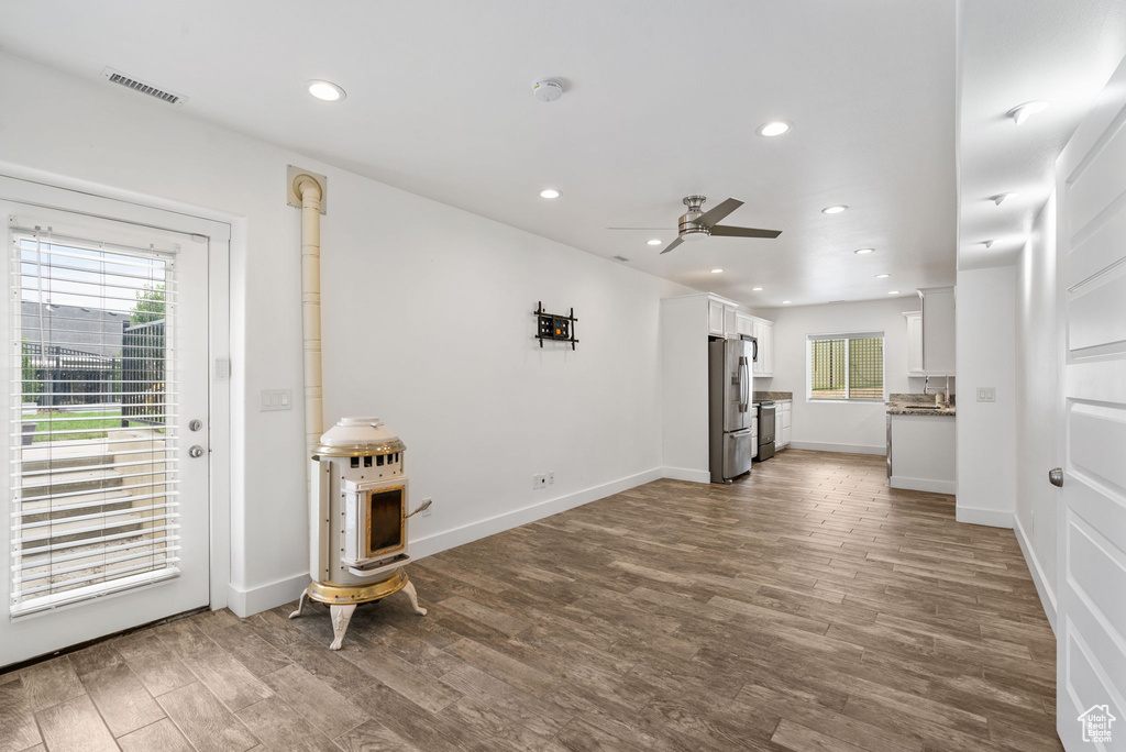 Unfurnished living room featuring dark wood-style floors, ceiling fan, recessed lighting, and a wood stove