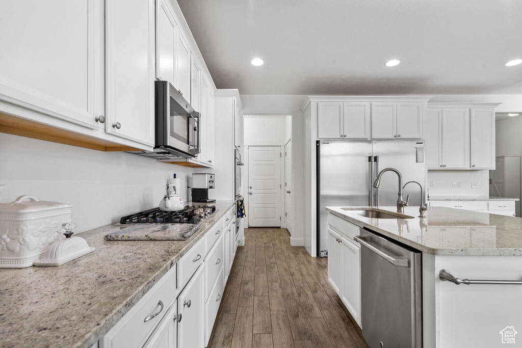 Kitchen with appliances with stainless steel finishes, white cabinetry, dark wood-style floors, recessed lighting, and light stone countertops