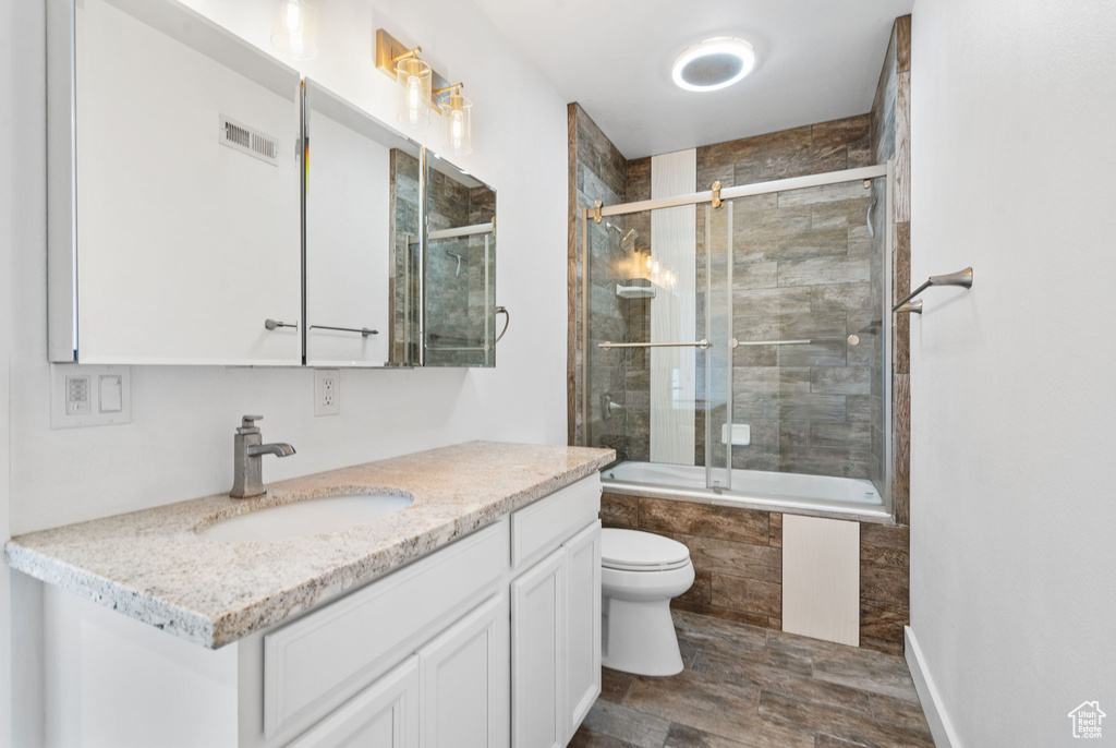 Full bath featuring vanity, tiled shower / bath combo, and wood finished floors