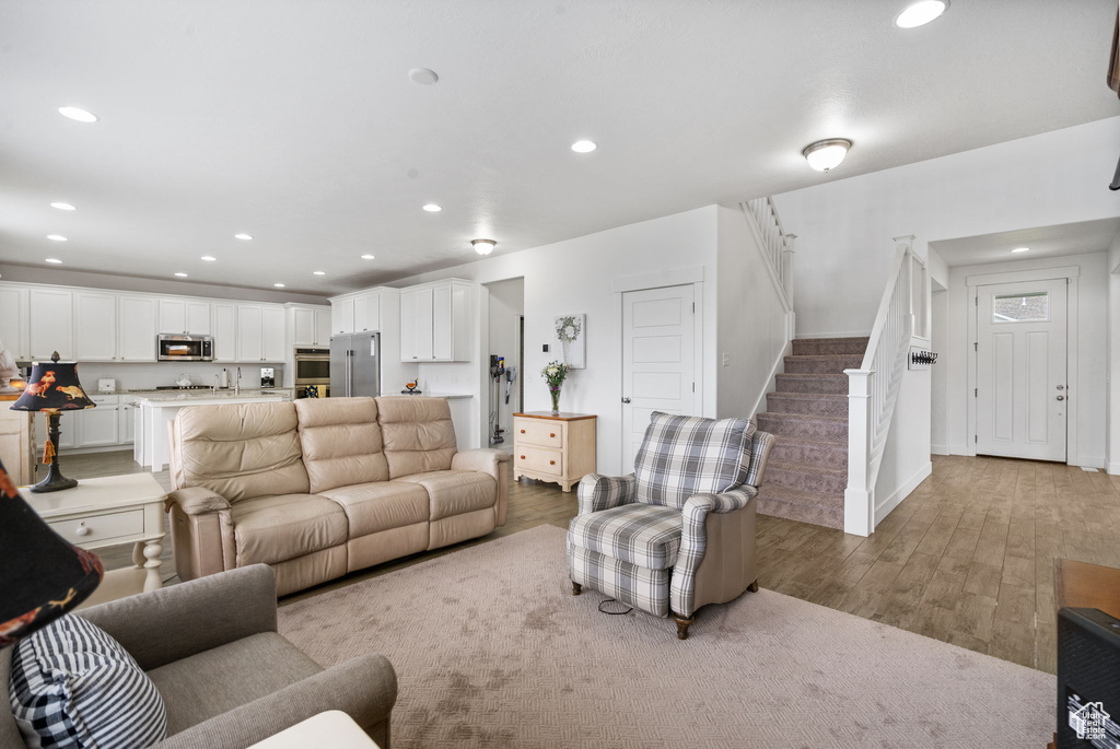 Living area with light wood-style flooring, stairway, and recessed lighting