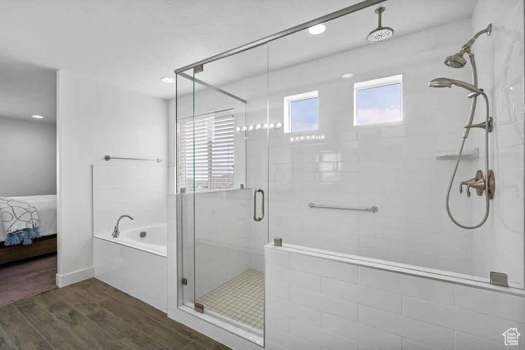 Ensuite bathroom featuring wood finished floors, a shower stall, a bath, and recessed lighting