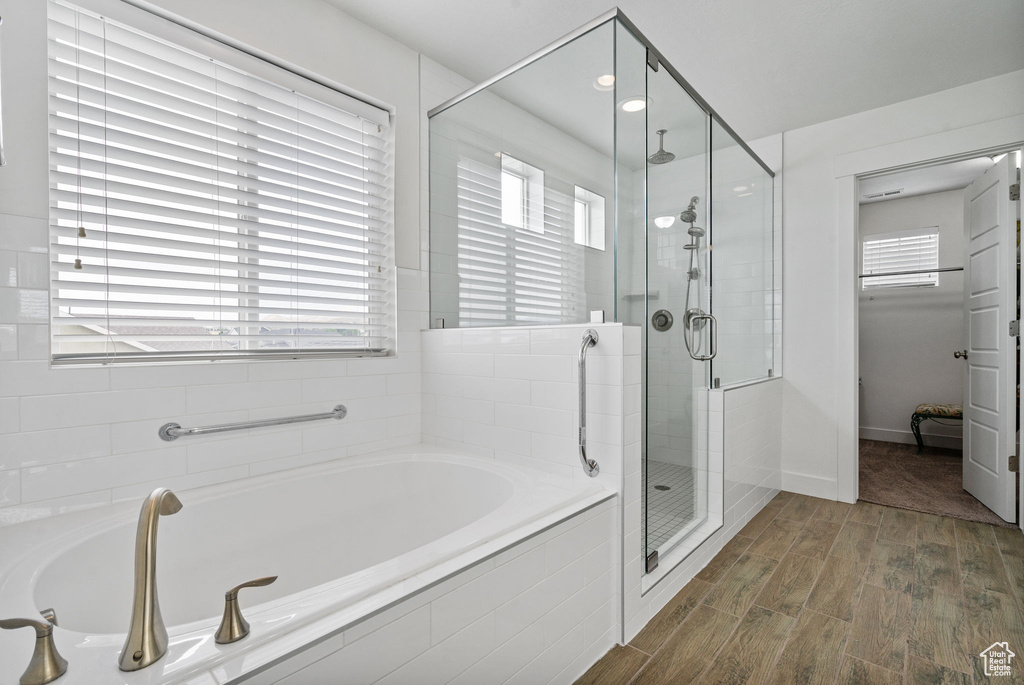 Bathroom featuring a stall shower, a garden tub, and wood finished floors
