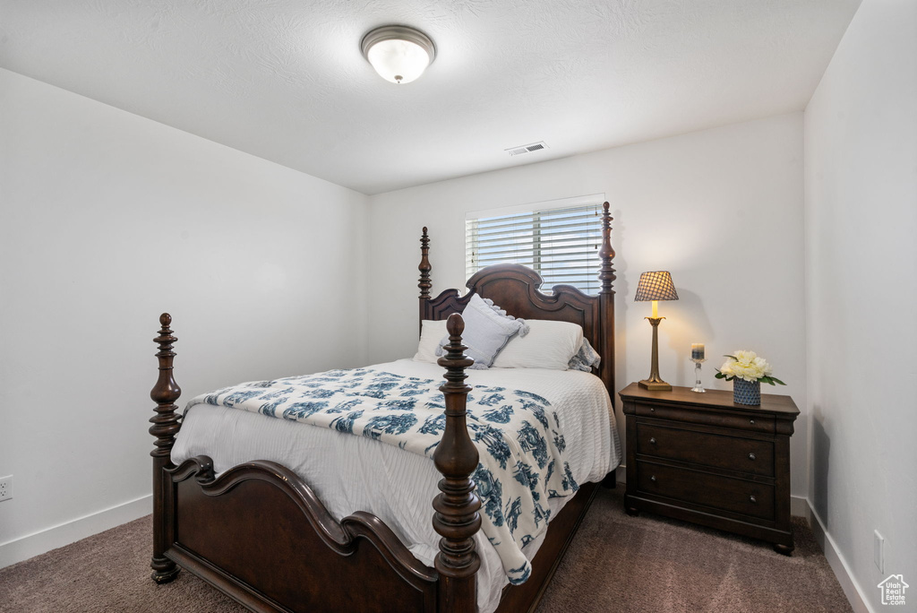 Bedroom featuring dark colored carpet and baseboards