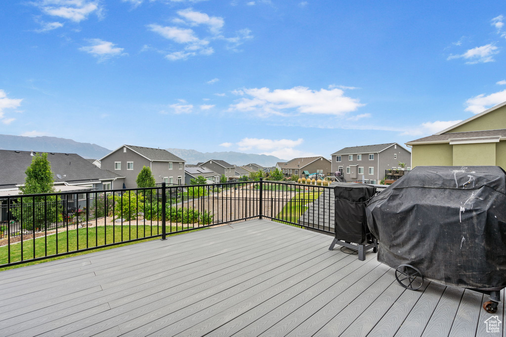 Wooden terrace with a residential view, a grill, a mountain view, and a yard