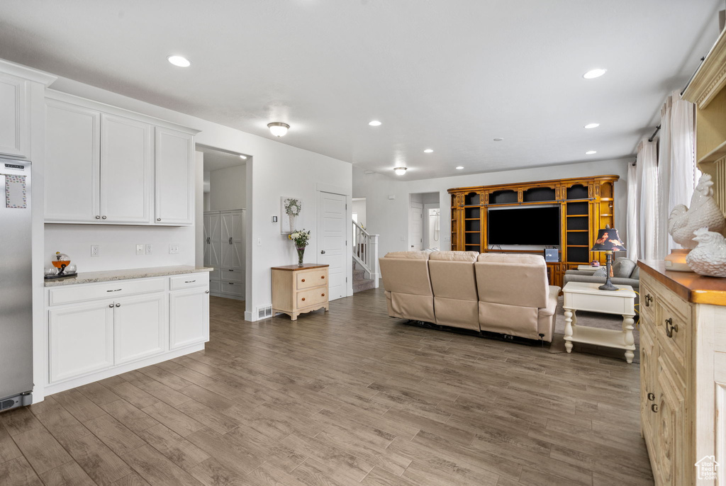 Living room with wood finished floors, stairway, and recessed lighting