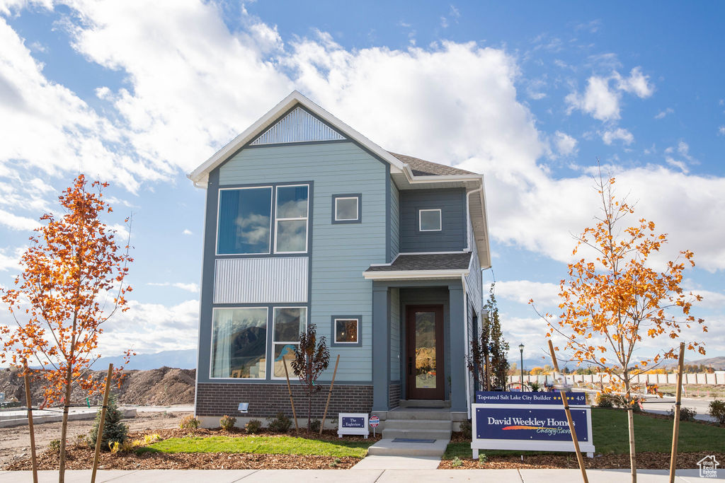 View of front of house with a shingled roof and brick siding