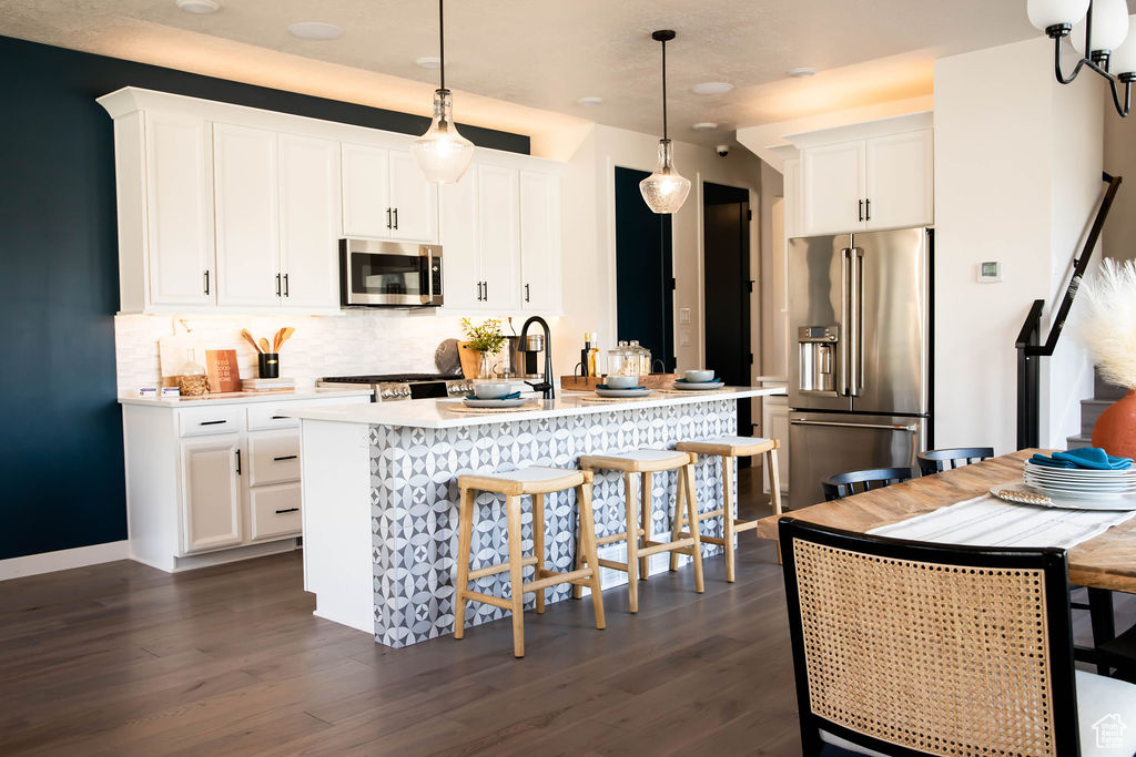 Kitchen with stainless steel appliances, light countertops, backsplash, and dark wood-type flooring