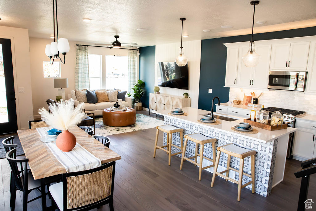 Kitchen with ceiling fan, stainless steel appliances, tasteful backsplash, dark wood-style floors, and light countertops