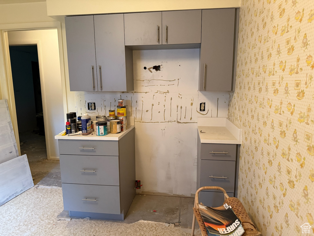 Kitchen featuring gray cabinetry, wallpapered walls, and light countertops
