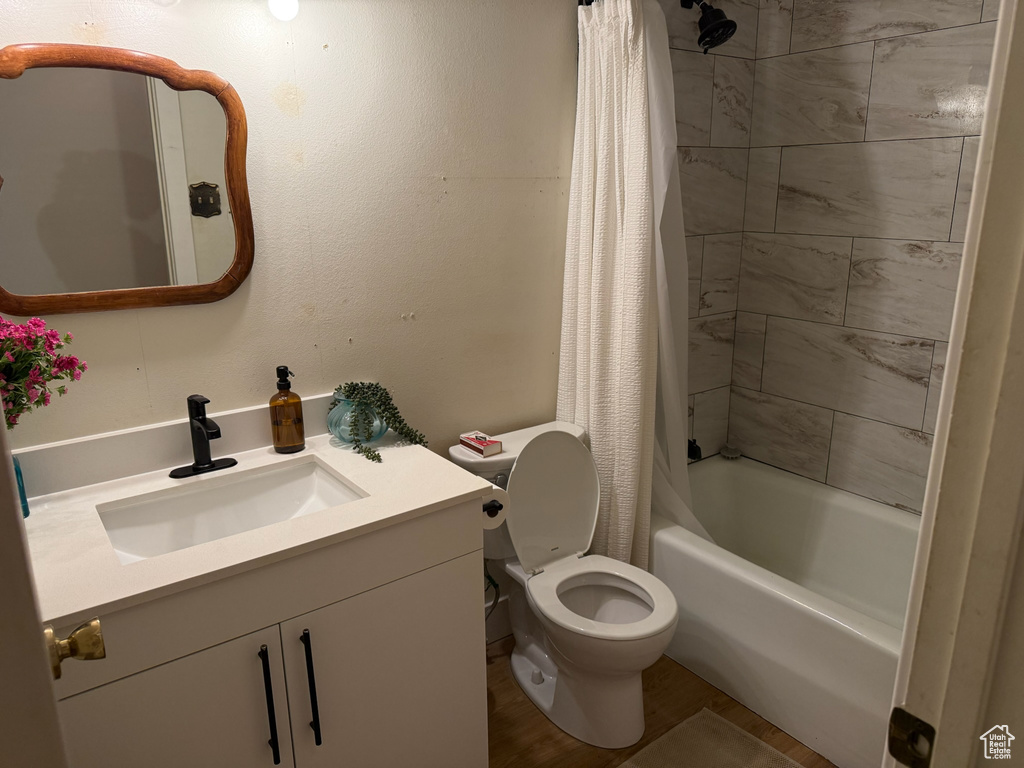 Bathroom with vanity, shower / bathtub combination with curtain, and wood finished floors