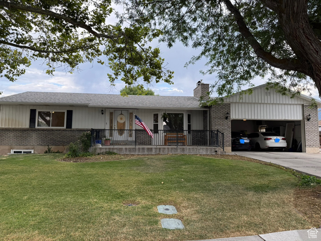 Single story home with an attached garage, a front lawn, brick siding, a chimney, and driveway