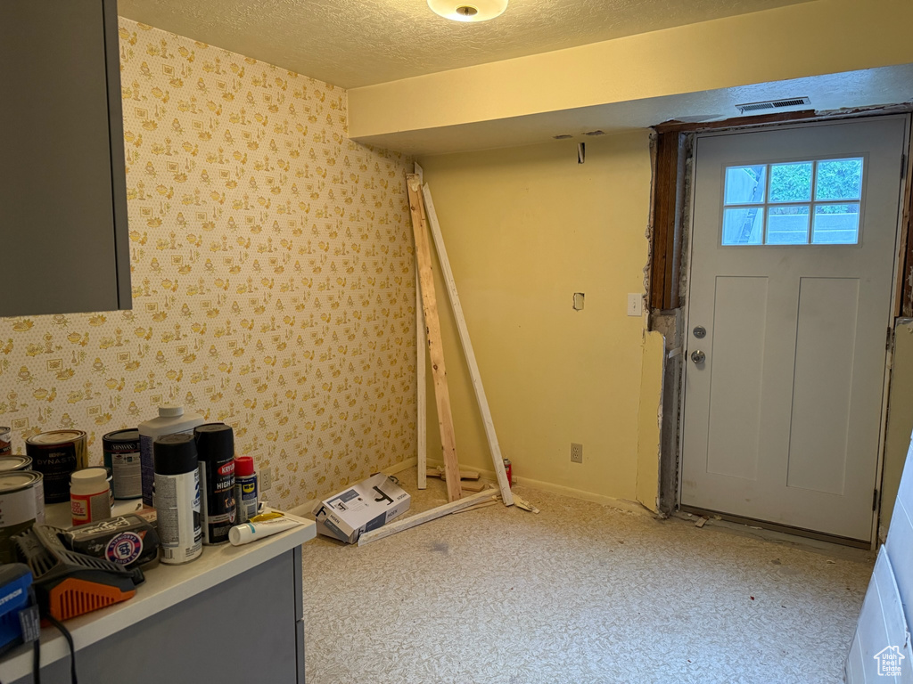 Foyer with a textured ceiling and wallpapered walls