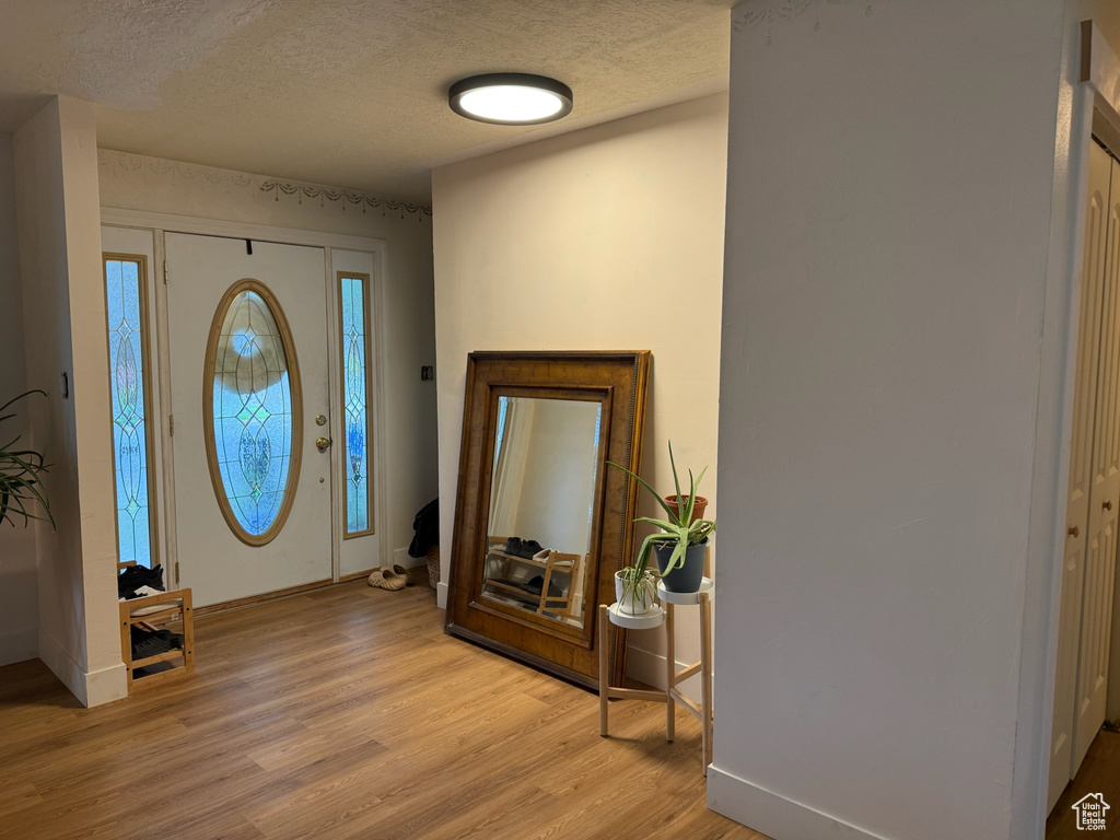 Foyer featuring light wood-style flooring and a textured ceiling
