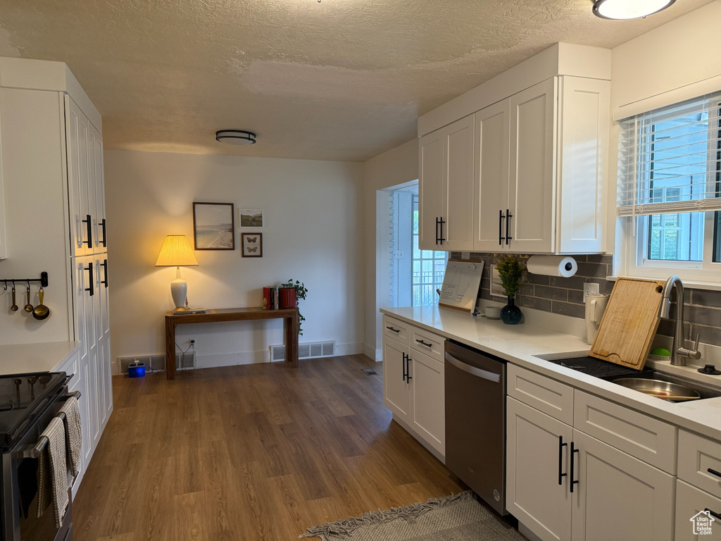 Kitchen featuring dark wood-type flooring, dishwasher, tasteful backsplash, light countertops, and a textured ceiling