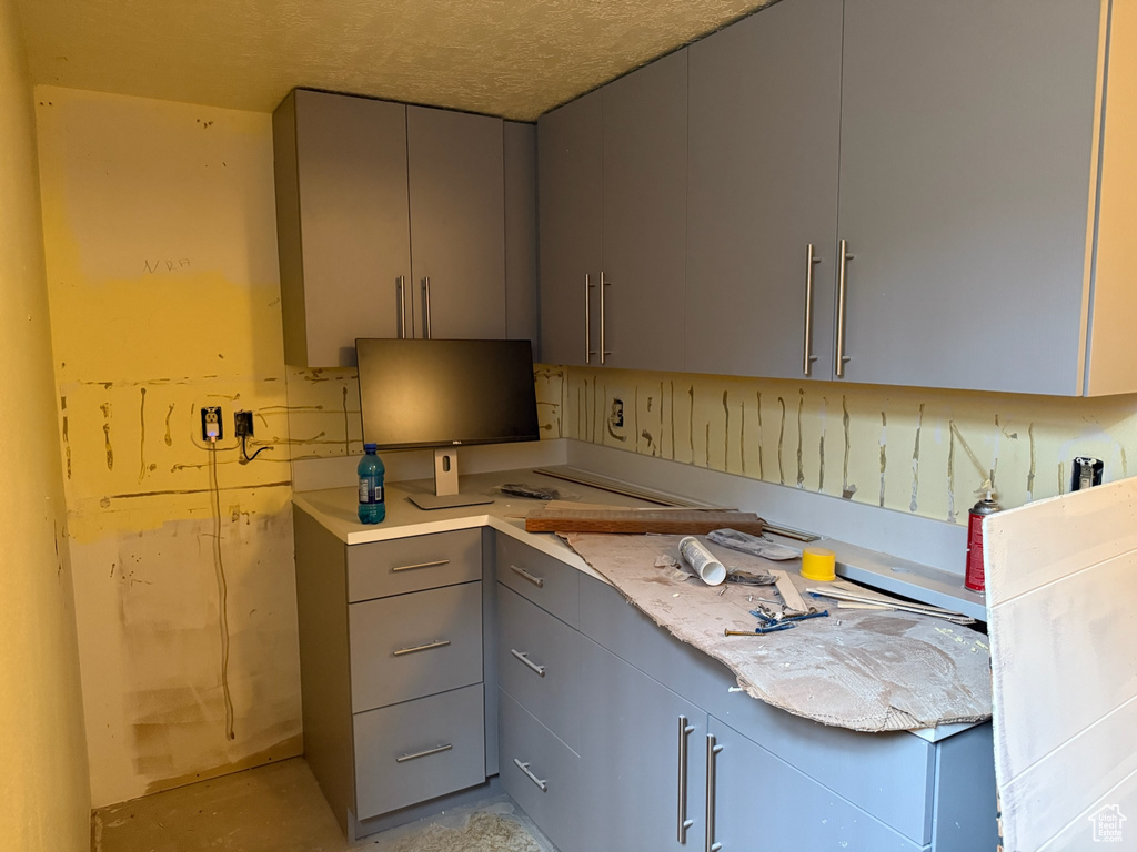 Kitchen featuring gray cabinetry, light countertops, and unfinished concrete floors