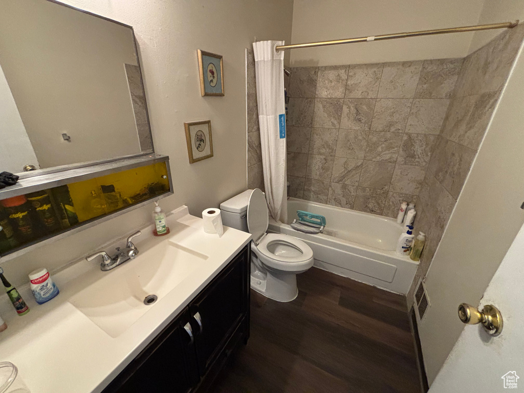 Full bath with wood finished floors, shower / tub combo with curtain, and vanity