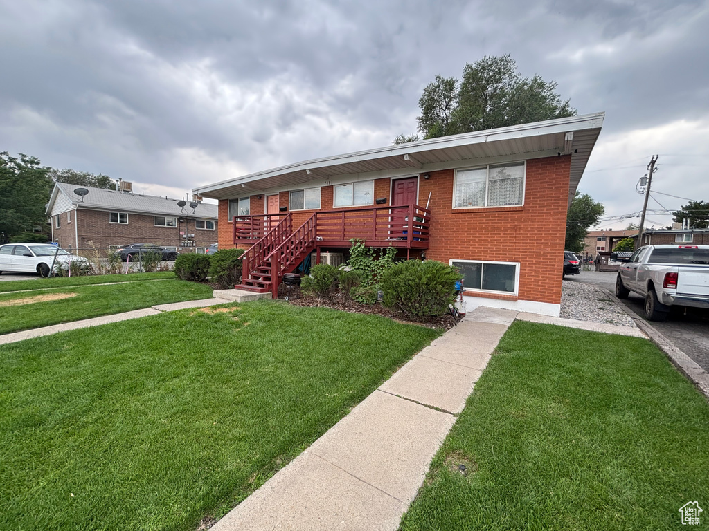 View of front of house featuring brick siding, a front lawn, and stairway