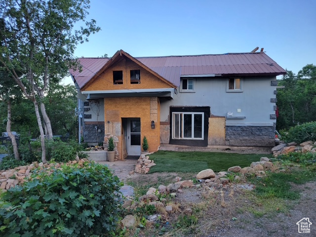 View of front of house featuring stone siding, a front lawn, and a metal roof