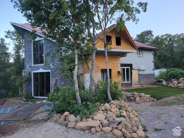 Rear view of house featuring stone siding and stucco siding