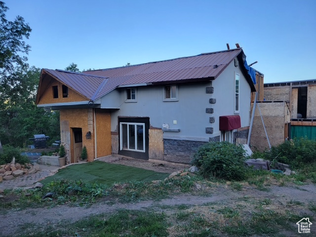 Back of property featuring stucco siding and a metal roof