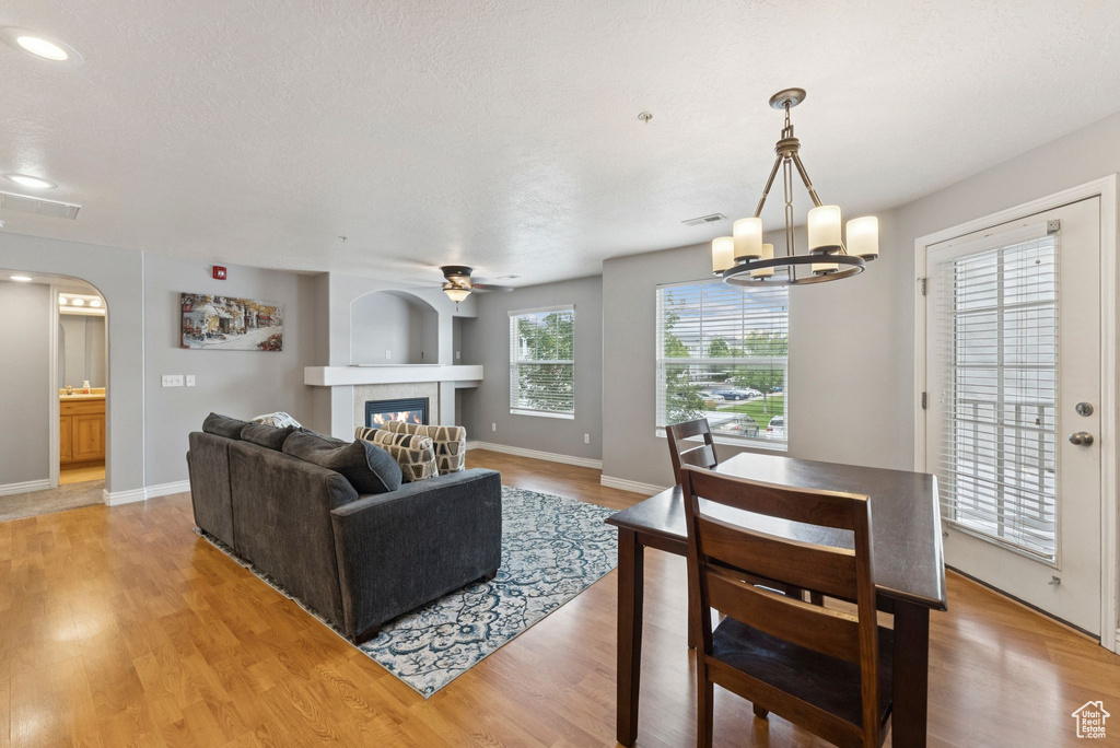 Living area featuring arched walkways, light wood-style flooring, a fireplace, a ceiling fan, and recessed lighting