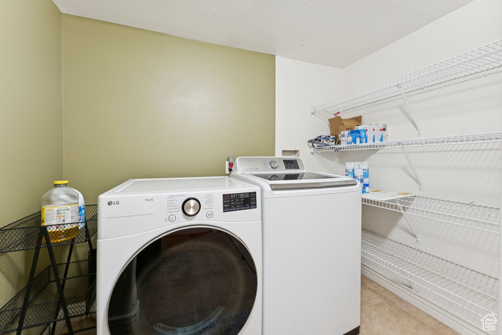 Washroom with washer and dryer and tile patterned floors