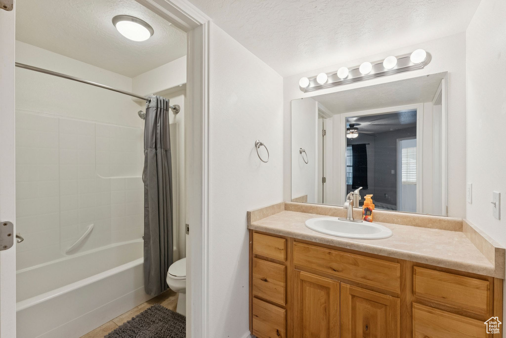 Bathroom featuring shower / bath combo, vanity, tile patterned floors, a ceiling fan, and a textured ceiling