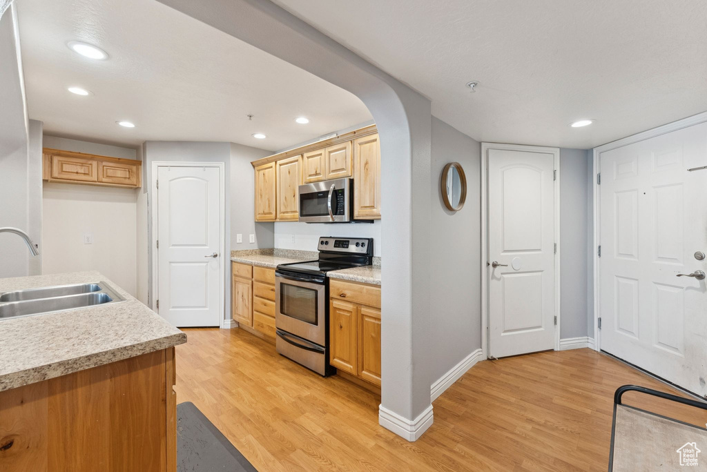 Kitchen with stainless steel appliances, light wood-style flooring, light countertops, recessed lighting, and light brown cabinets