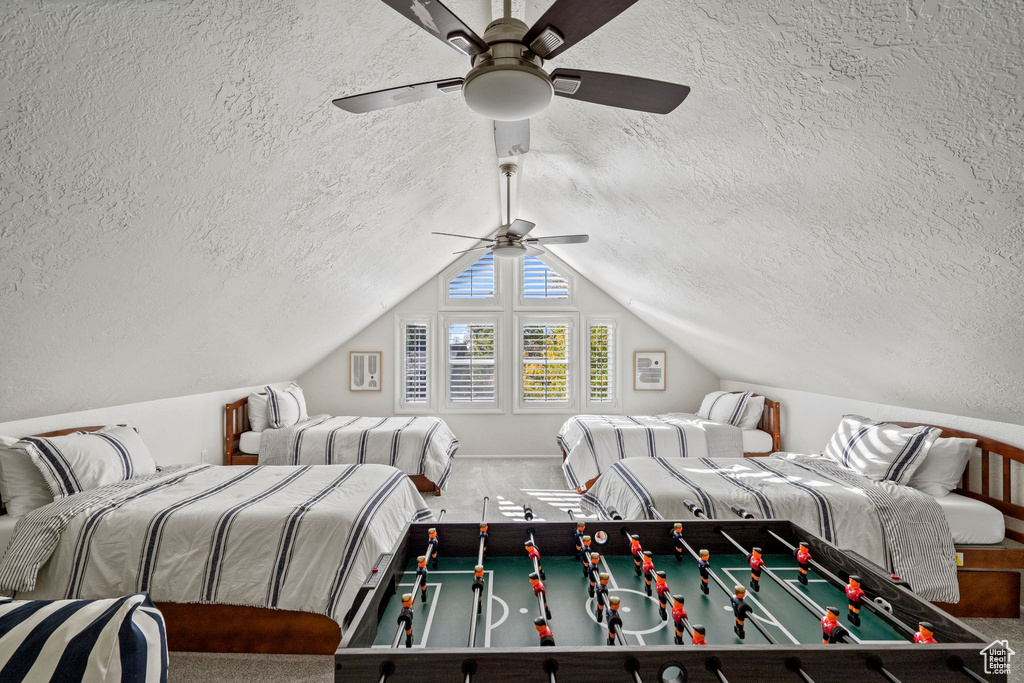 Bedroom featuring a textured ceiling, carpet, vaulted ceiling, and ceiling fan