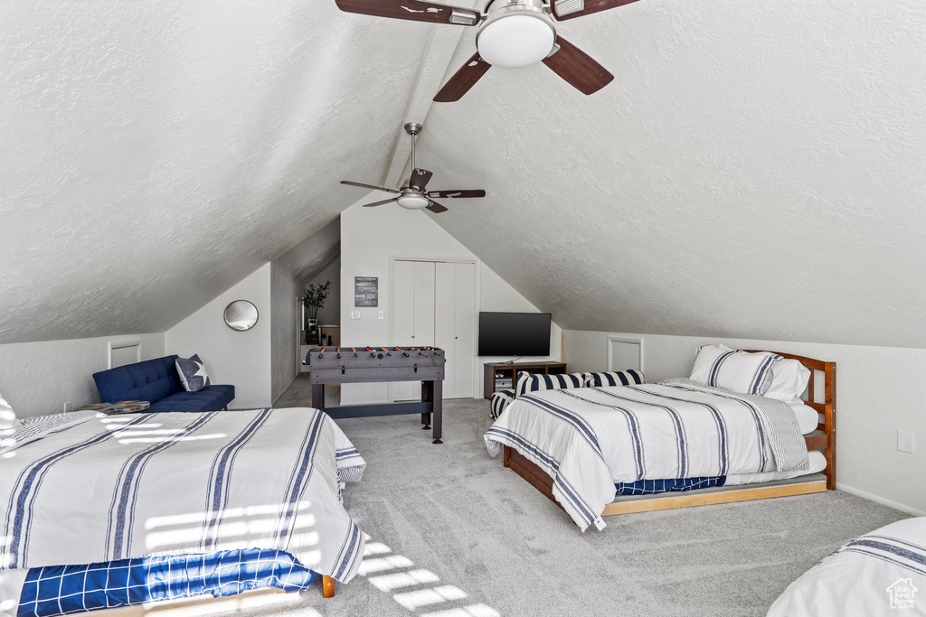 Bedroom with a textured ceiling, carpet flooring, lofted ceiling, and a ceiling fan