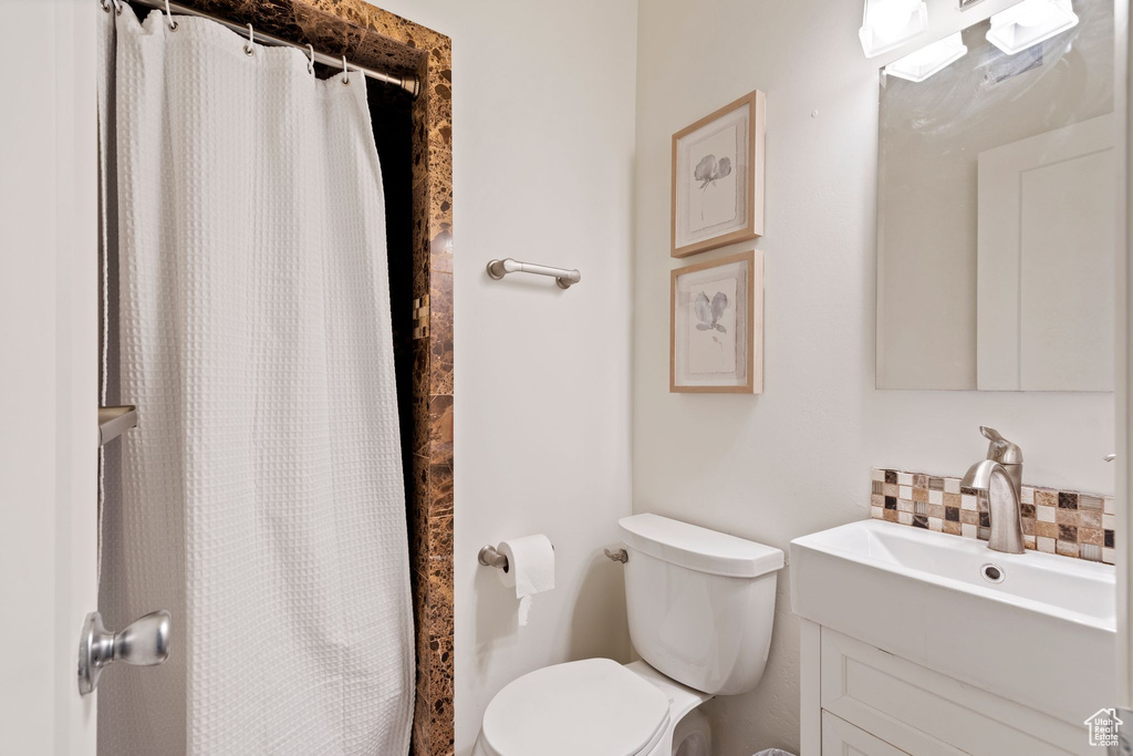 Bathroom featuring vanity, backsplash, and curtained shower