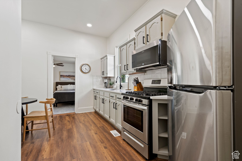 Kitchen featuring appliances with stainless steel finishes, tasteful backsplash, light countertops, dark wood finished floors, and recessed lighting