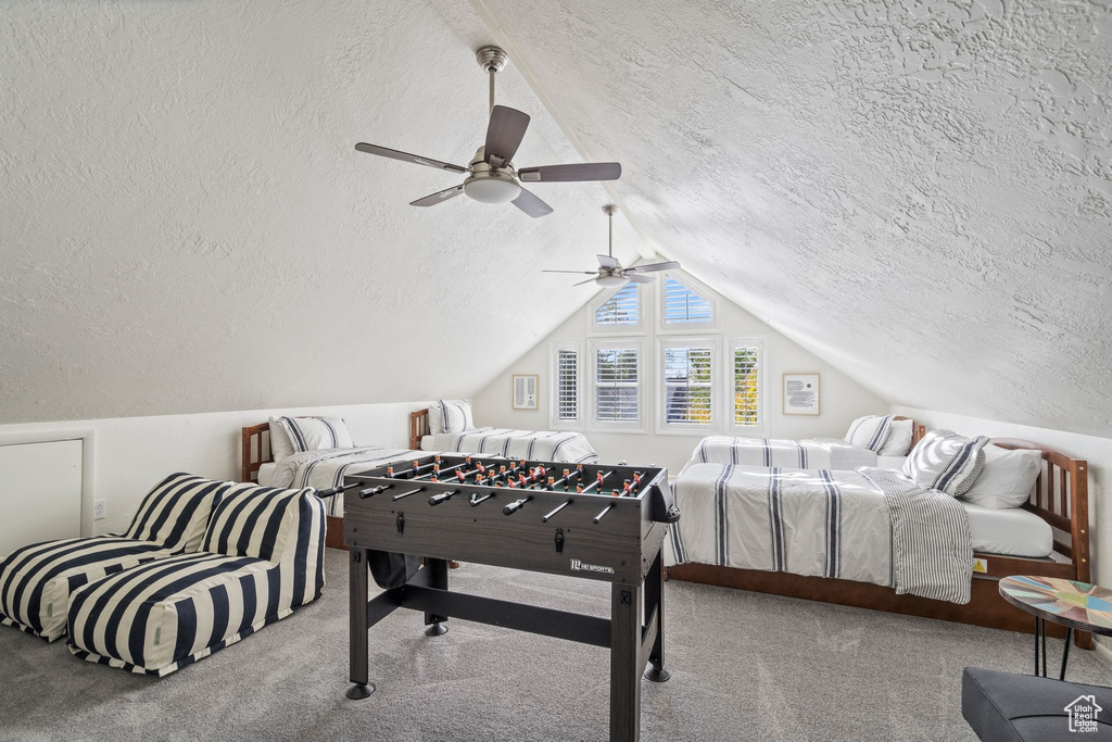 Carpeted bedroom featuring a textured ceiling, vaulted ceiling, and ceiling fan