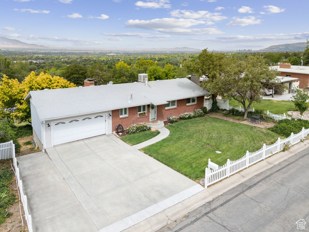 Ranch-style house featuring a chimney, a garage, concrete driveway, and a mountain view
