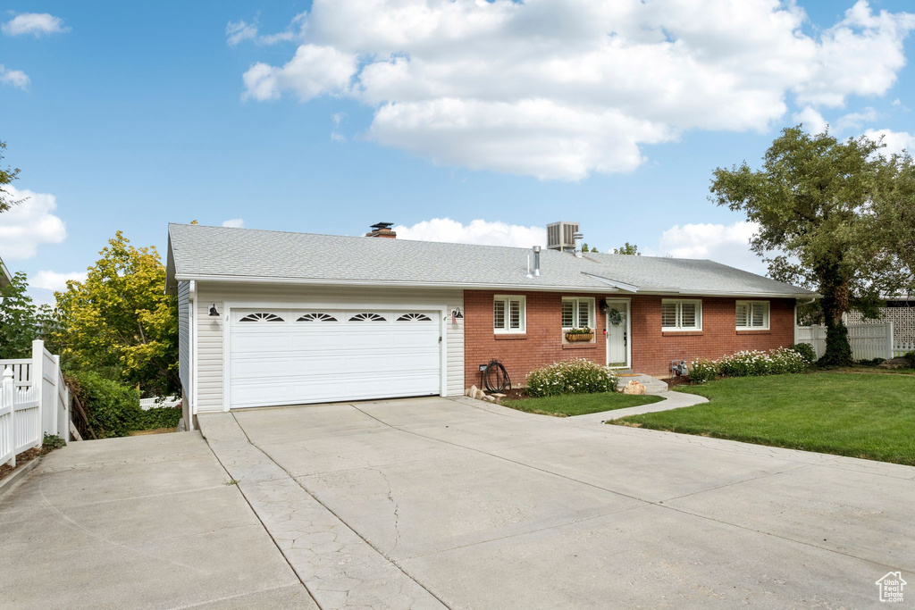 Ranch-style home with driveway, a garage, a chimney, brick siding, and a shingled roof