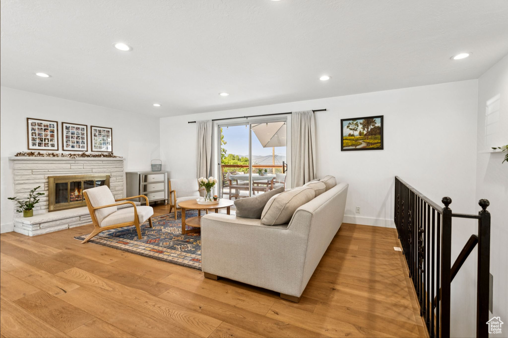 Living area with wood finished floors, recessed lighting, and a stone fireplace