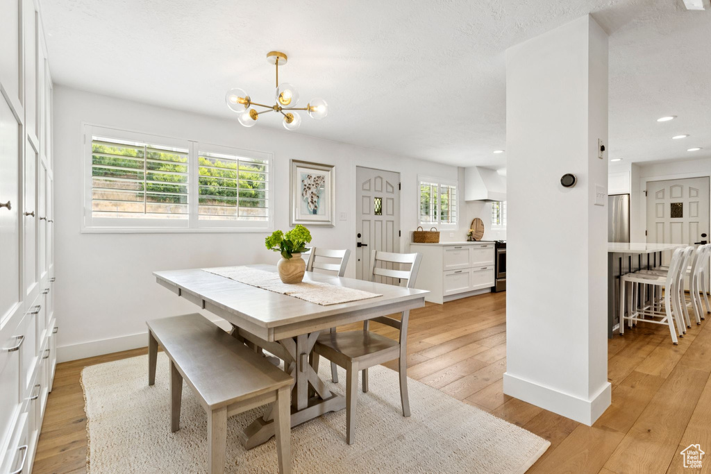 Dining room featuring plenty of natural light, light wood finished floors, a chandelier, and recessed lighting