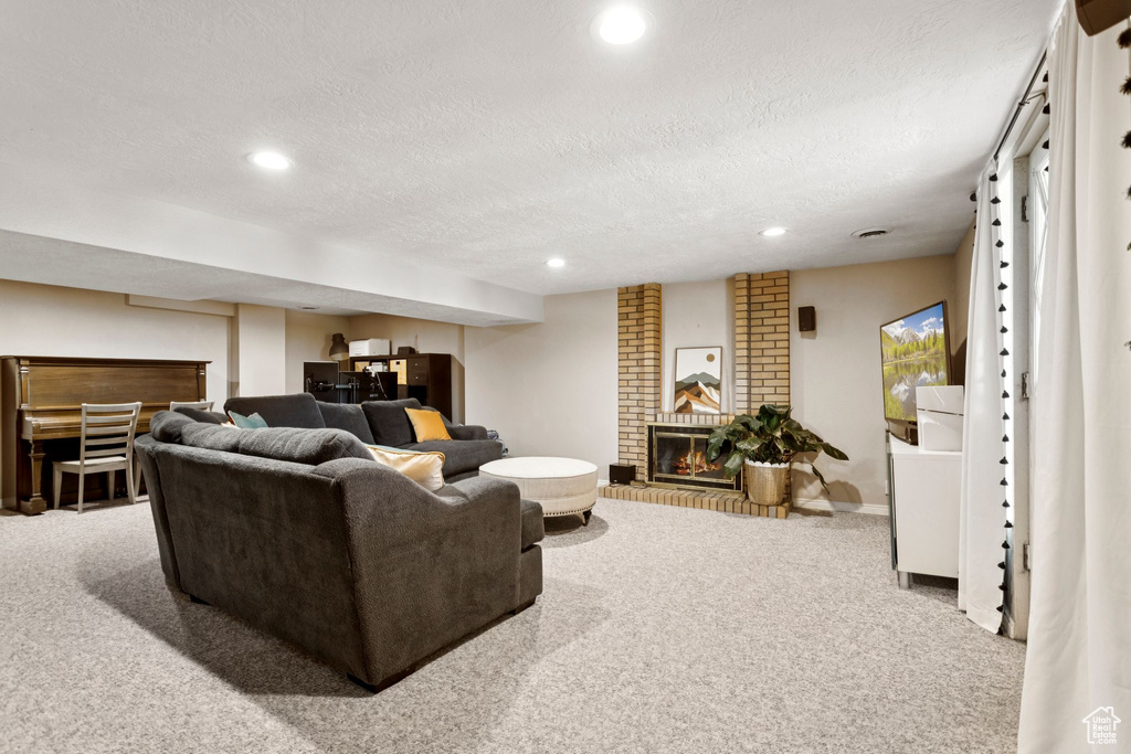 Carpeted living area featuring a textured ceiling, recessed lighting, a brick fireplace, and a dry bar