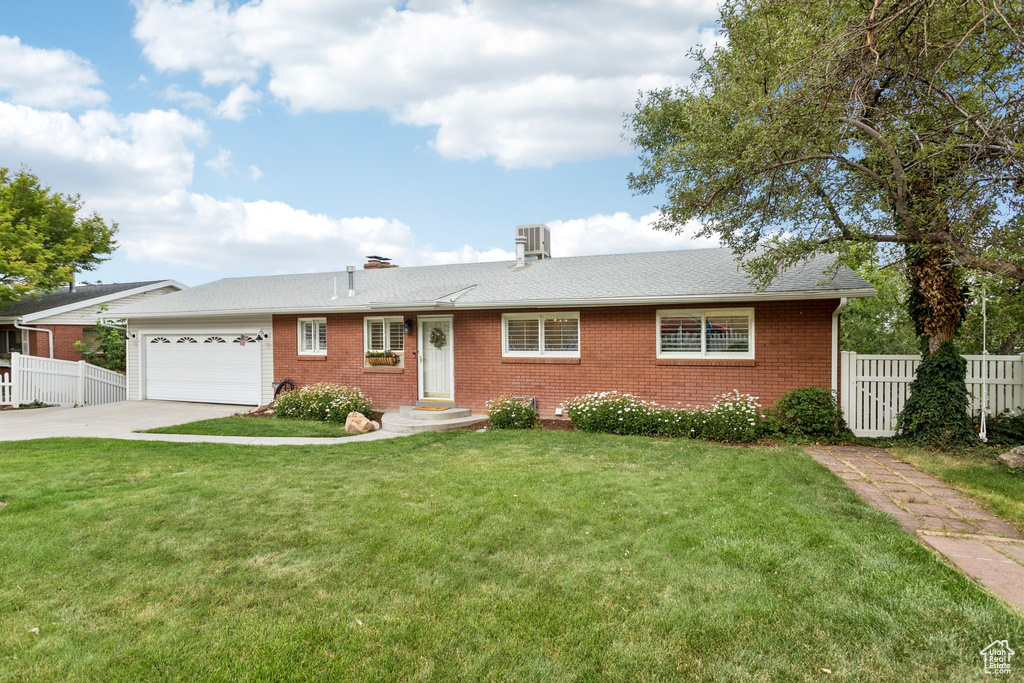 Ranch-style house with a garage, concrete driveway, brick siding, roof with shingles, and a chimney