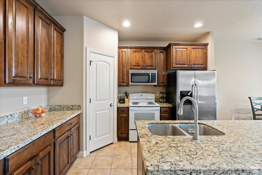 Kitchen with appliances with stainless steel finishes, light tile patterned flooring, light stone countertops, and recessed lighting