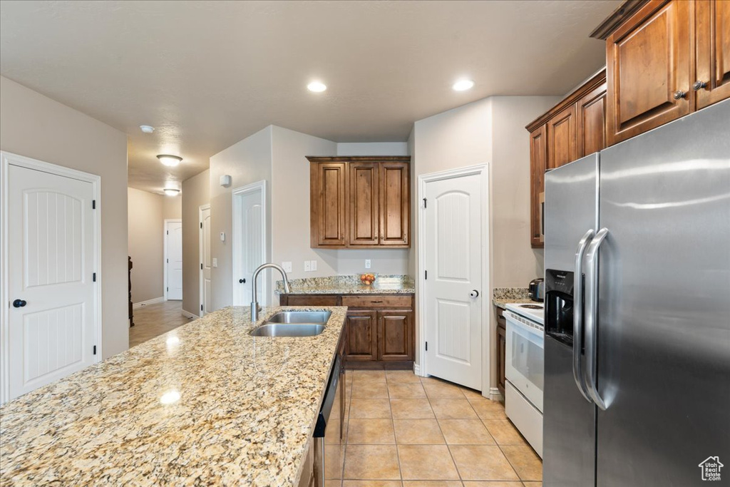 Kitchen with stainless steel appliances, light stone countertops, light tile patterned flooring, recessed lighting, and brown cabinets