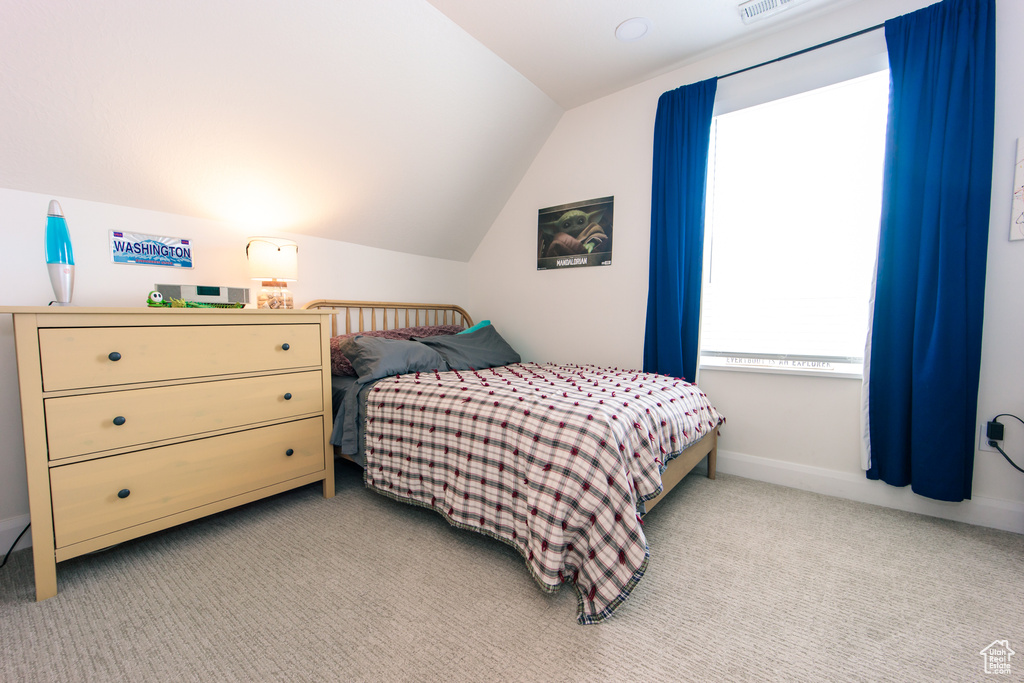 Bedroom with lofted ceiling and light colored carpet