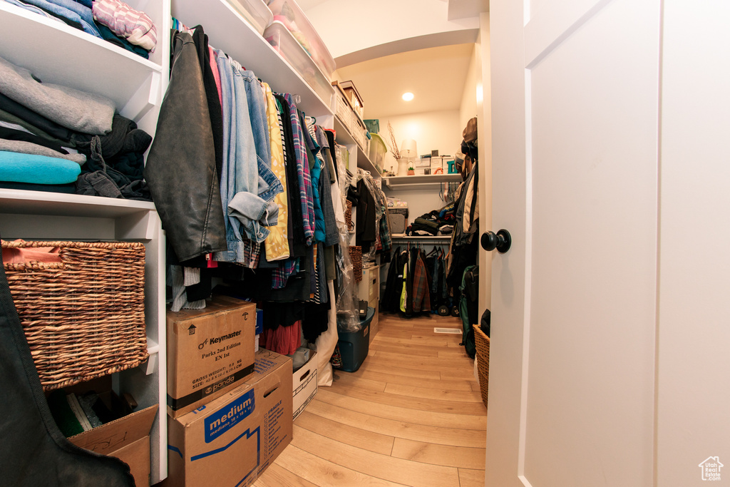 Spacious closet featuring light wood-style floors and arched walkways