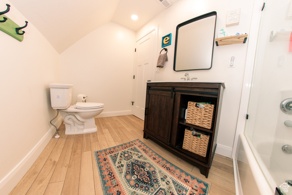 Full bath featuring wood-type flooring, vanity, lofted ceiling, and bathtub / shower combination