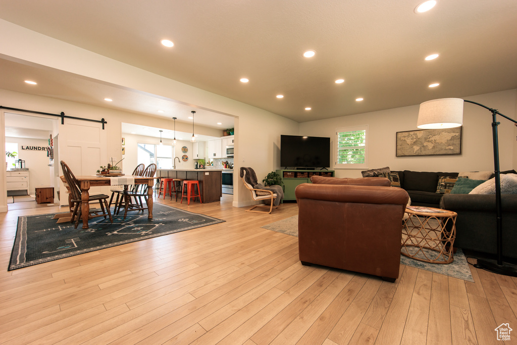 Living area with a barn door, light wood-type flooring, and recessed lighting