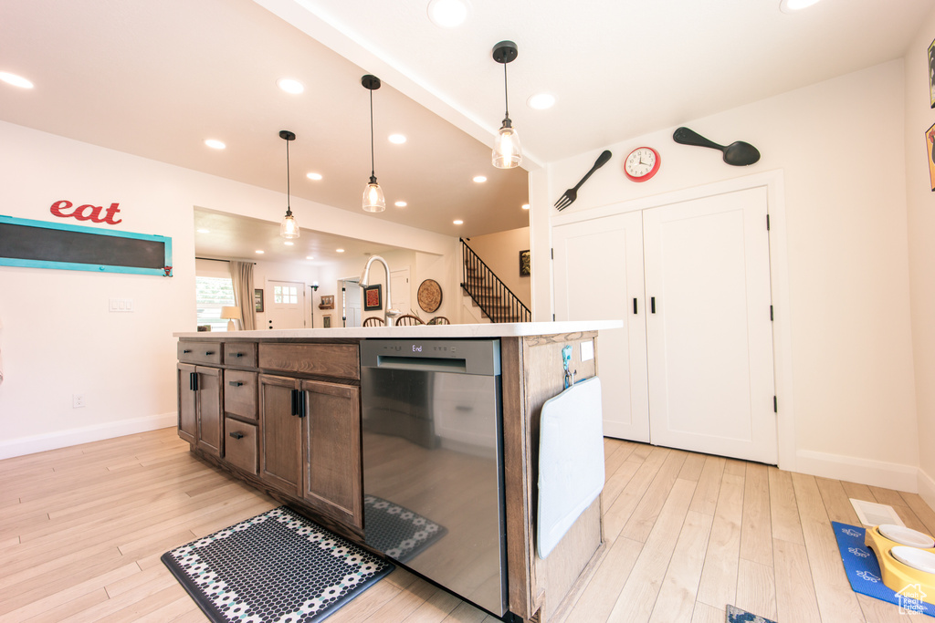 Kitchen featuring stainless steel dishwasher, a kitchen island with sink, light wood finished floors, decorative light fixtures, and recessed lighting