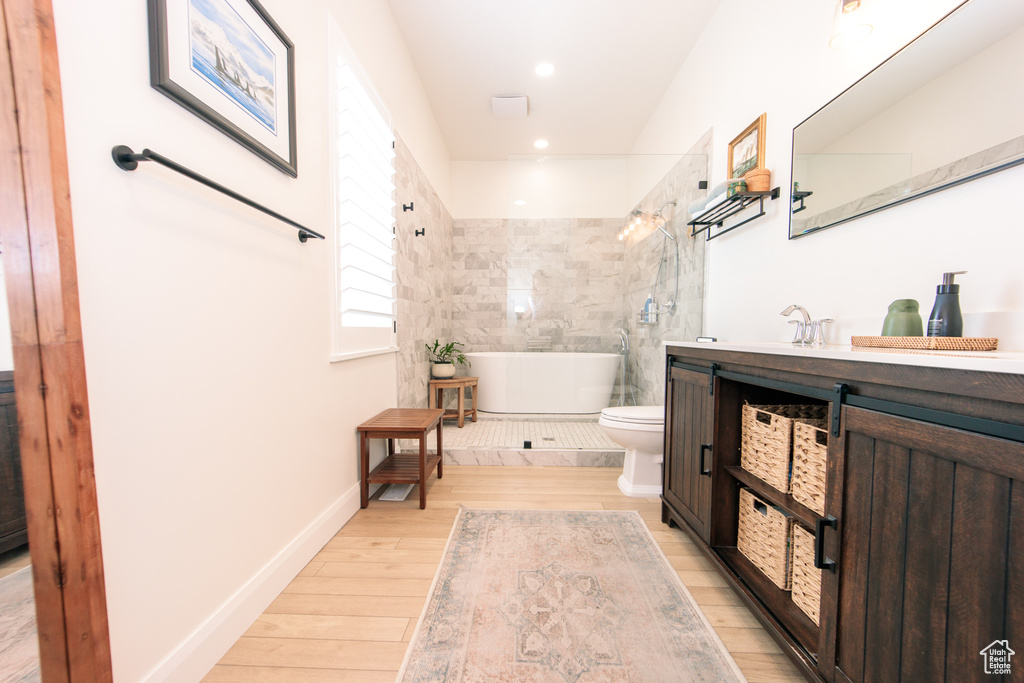 Bathroom featuring a freestanding tub, vanity, wood finished floors, and recessed lighting